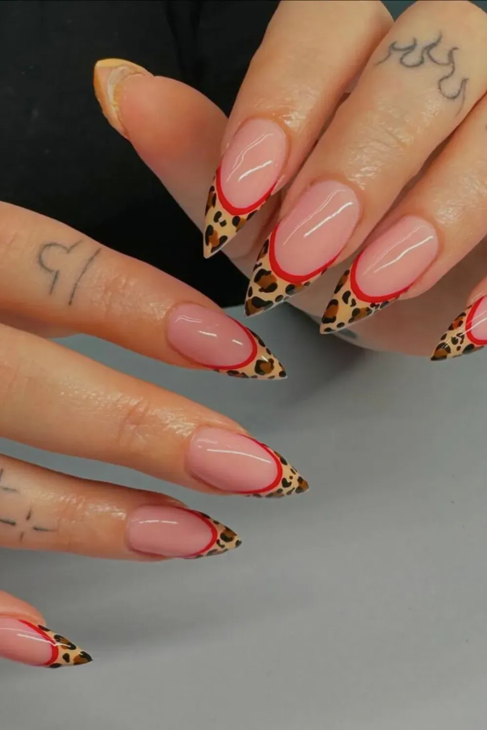 Red Lined Leopard French Alt Text: Almond nails with leopard print tips outlined in red polish.