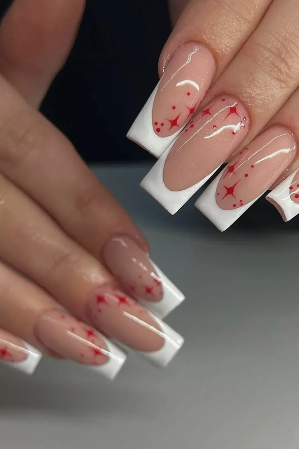 Red Sparkle Starburst Nails Alt Text: White french tips decorated with red sparkles and stars.