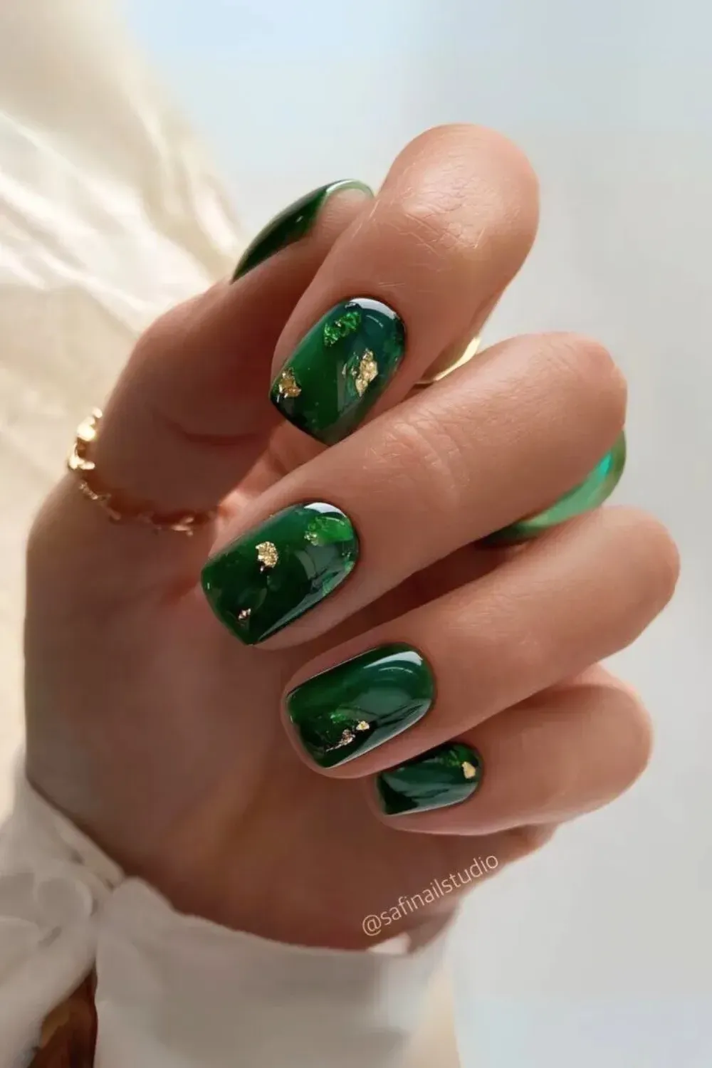 Emerald Green Marble Nails with Gold Flakes - Short square nails with a glossy, glass-like emerald green marble effect and suspended gold foil flakes.