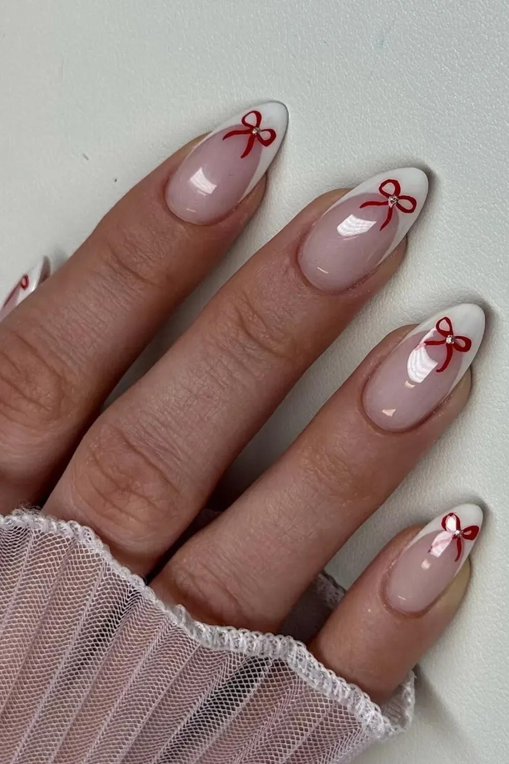 Elegant Red Bow Almond French: Long almond nails with white French tips and charming red bow details.