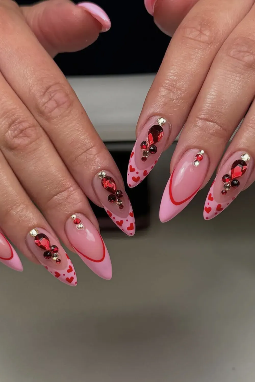 Ruby Gemstone Stiletto Nails Alt Text: Stiletto nails with red outline and large red ruby gems.