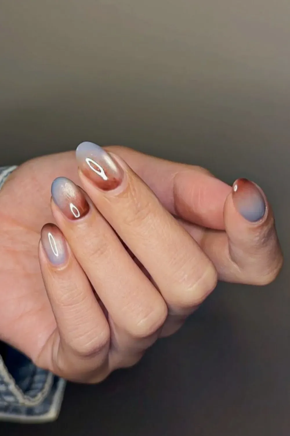 Vertical ombre nails fading from icy blue to warm brown cat eye on short nails.