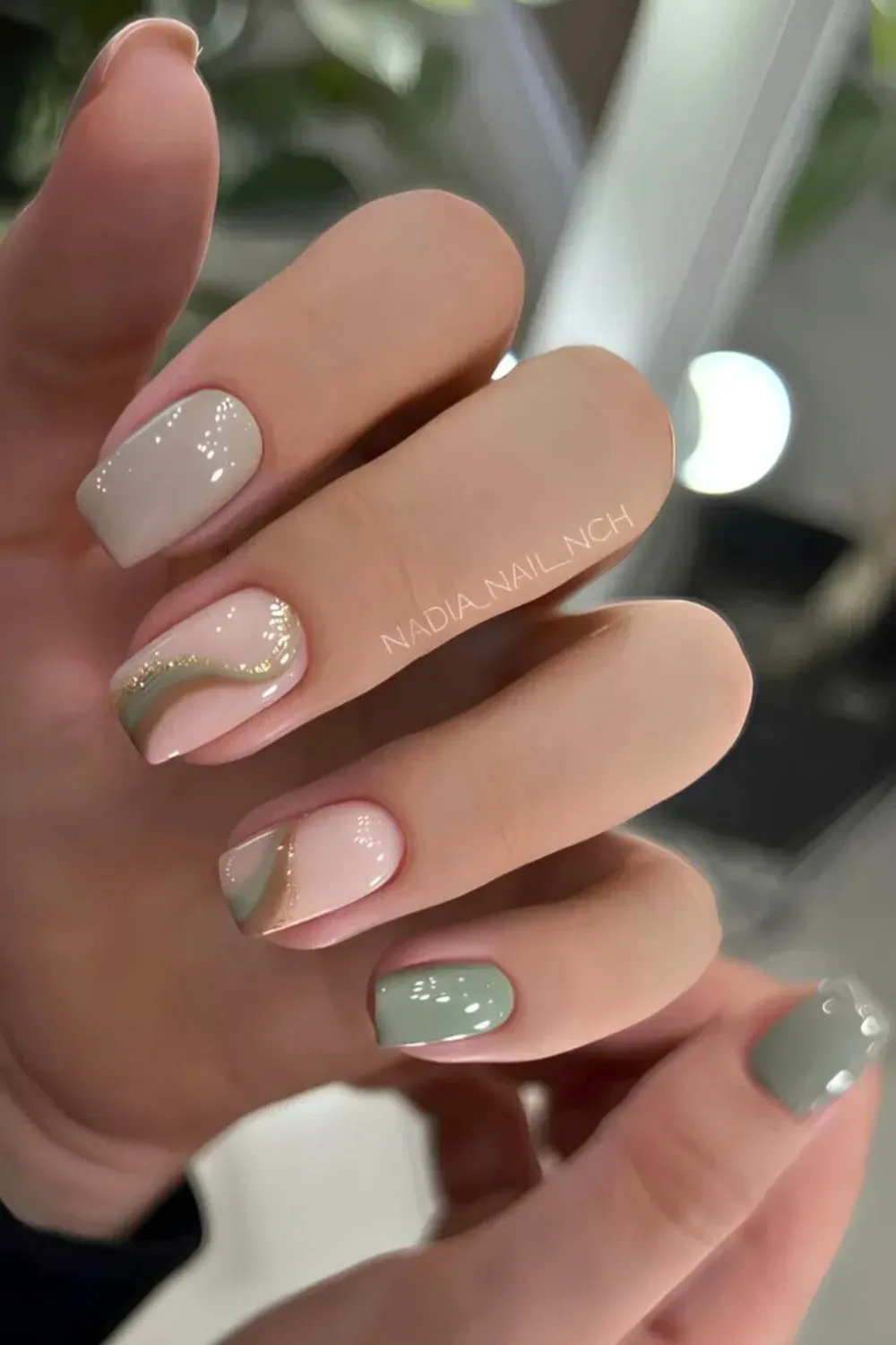 Soft Sage Swirl Art with Gold Glitter Accent - Short square nails with pastel green and neutral swirls, highlighted with fine gold glitter details.