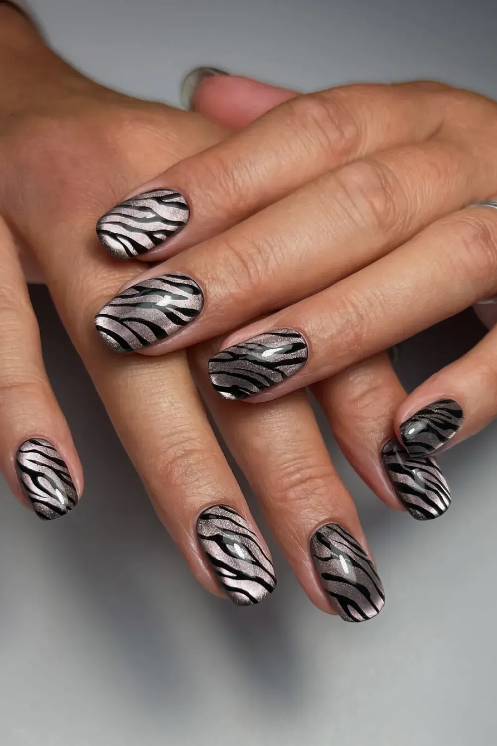 Bright silver cat eye nails with black zebra stripe print on short nails
