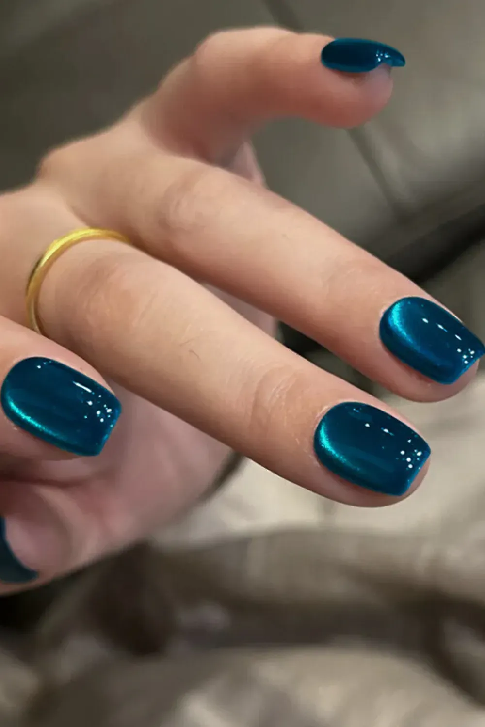 Short nails with vibrant deep teal blue cat eye polish and glossy finish