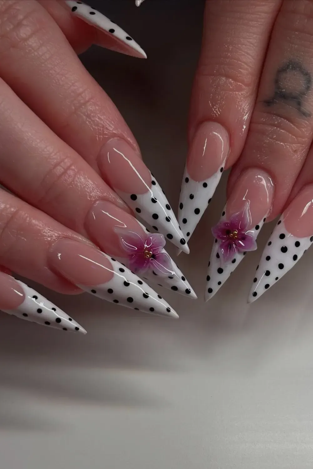 Polka Dot Orchid Nails Alt Text: White french tips with black dots and purple 3D orchid flower.