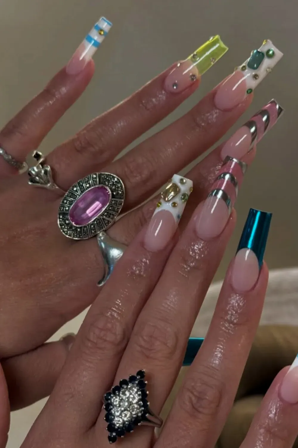 Mix And Match Chrome Nails Alt Text: Long nails with mixed designs of pink chrome, blue tips, and gems.