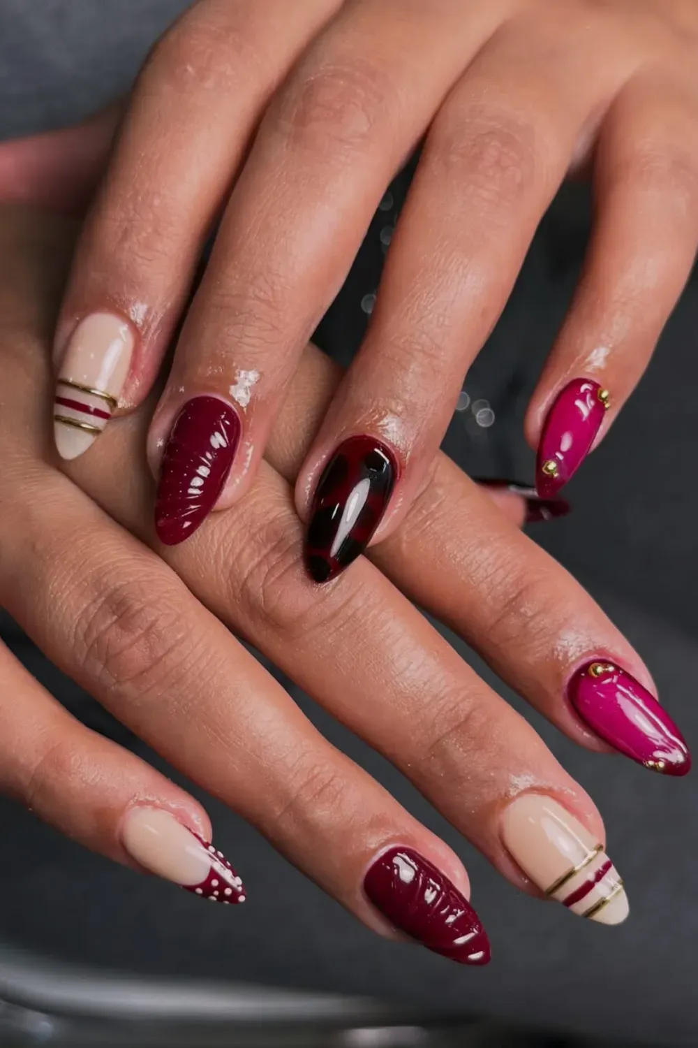 Elegant Red & Nude Bangle Nails for Fall with Gold Striping - A chic manicure featuring deep berry red, magenta, and nude nails, with thin gold 3D Bangle Nail lines on the accent fingers.