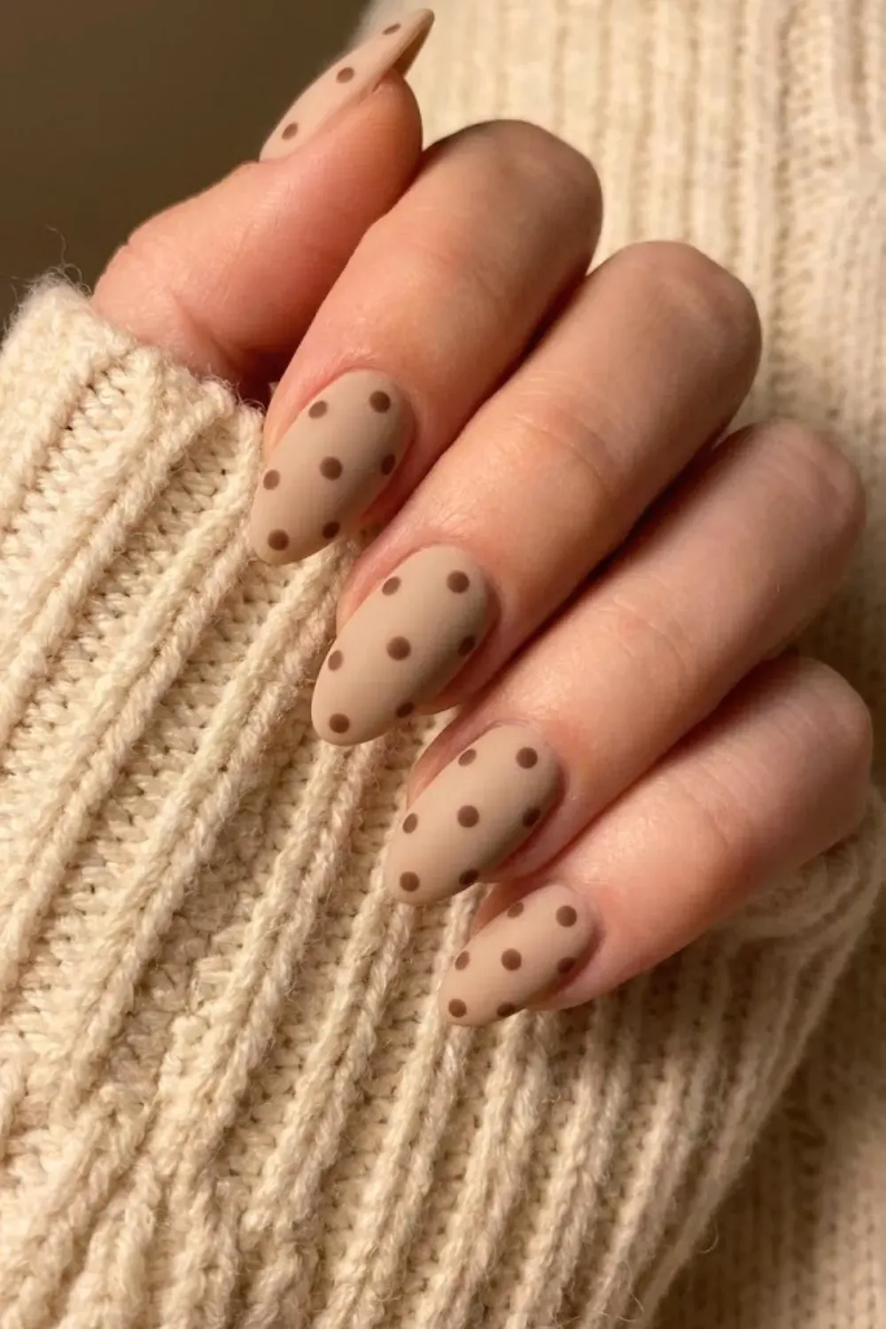 Matte Beige and Brown Polka Dot Nails - Matte finish almond nails in a cool beige color with dark brown polka dots near a beige sweater.