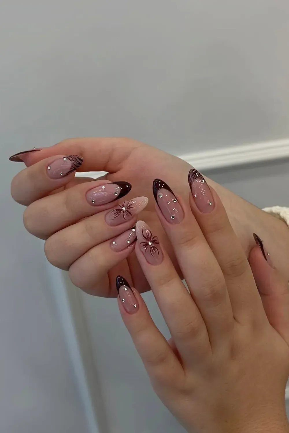 Burgundy French With Rhinestones Alt Text: Almond nails with dark red tips and starburst rhinestone design.