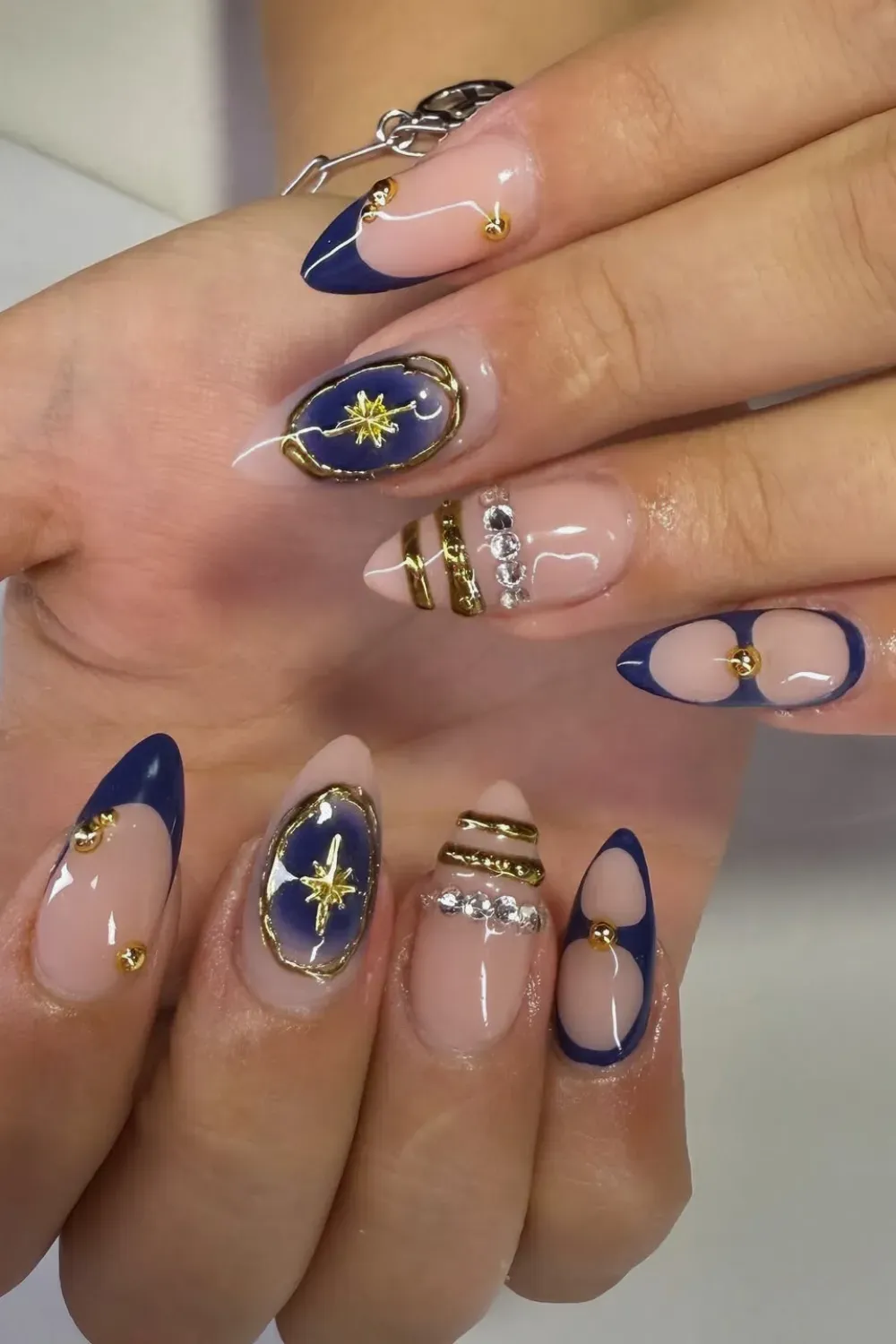 Navy Blue & Gold Aura Bangle Nails with Star Art - A sophisticated Bangle Manicure using navy blue polish, framed gold rings, and a 3D gold and rhinestone stacked band.