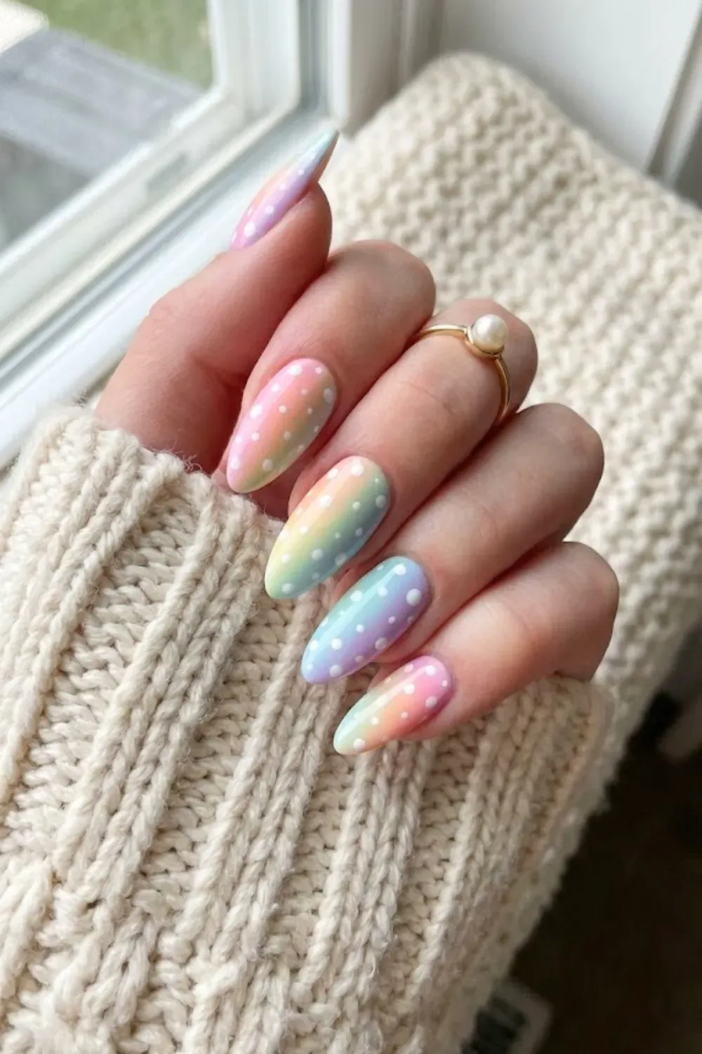 Pastel Rainbow Gradient Polka Dot Nails - Hand wearing a pearl ring showing almond nails with a vertical pastel rainbow gradient and white polka dots.