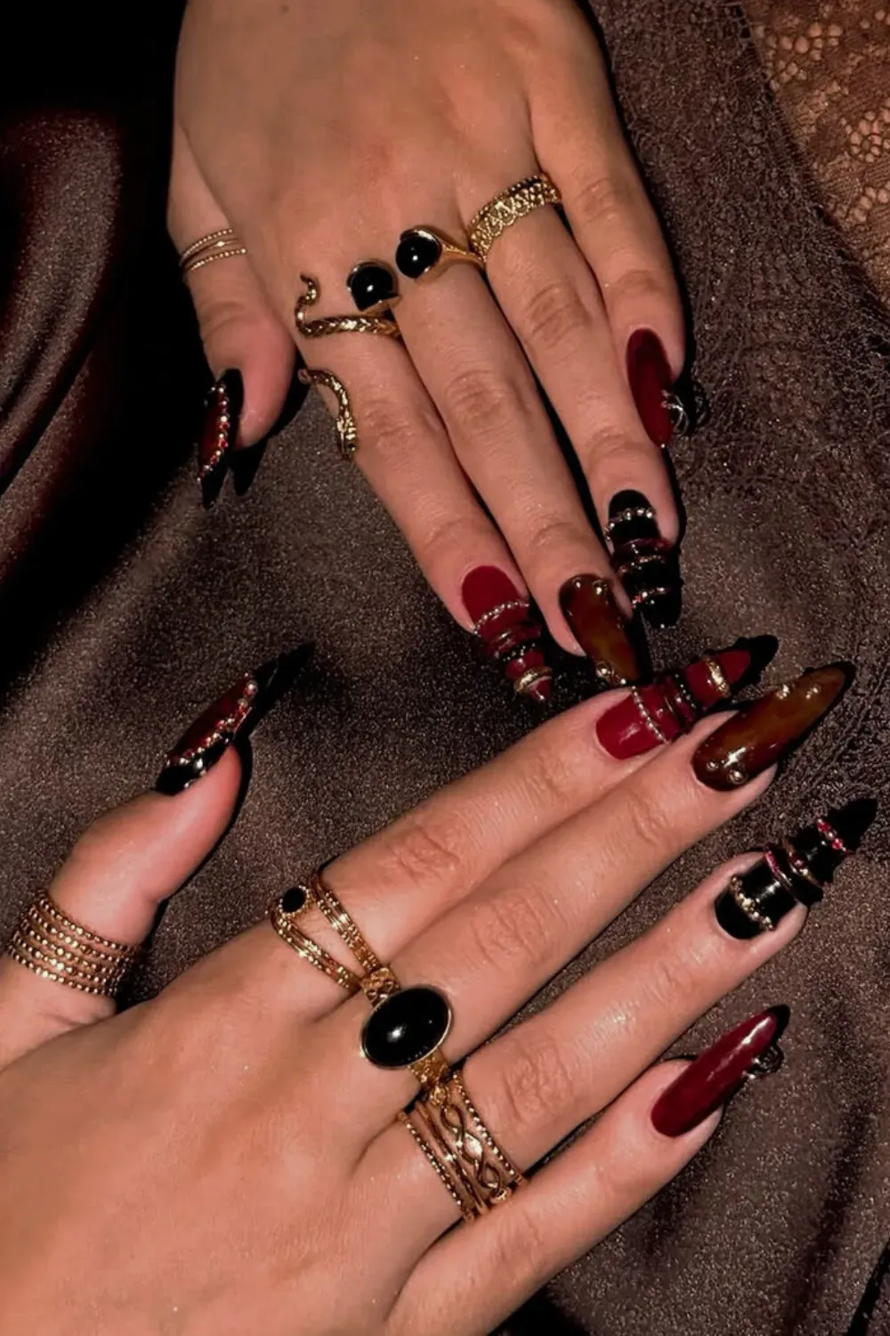 Black & Red Edgy Bangle Nails with Layered 3D Gold Rings - Long, dark stiletto nails featuring black and deep red polish, enhanced with layered 3D gold bands and red rhinestone accents for a dramatic look.