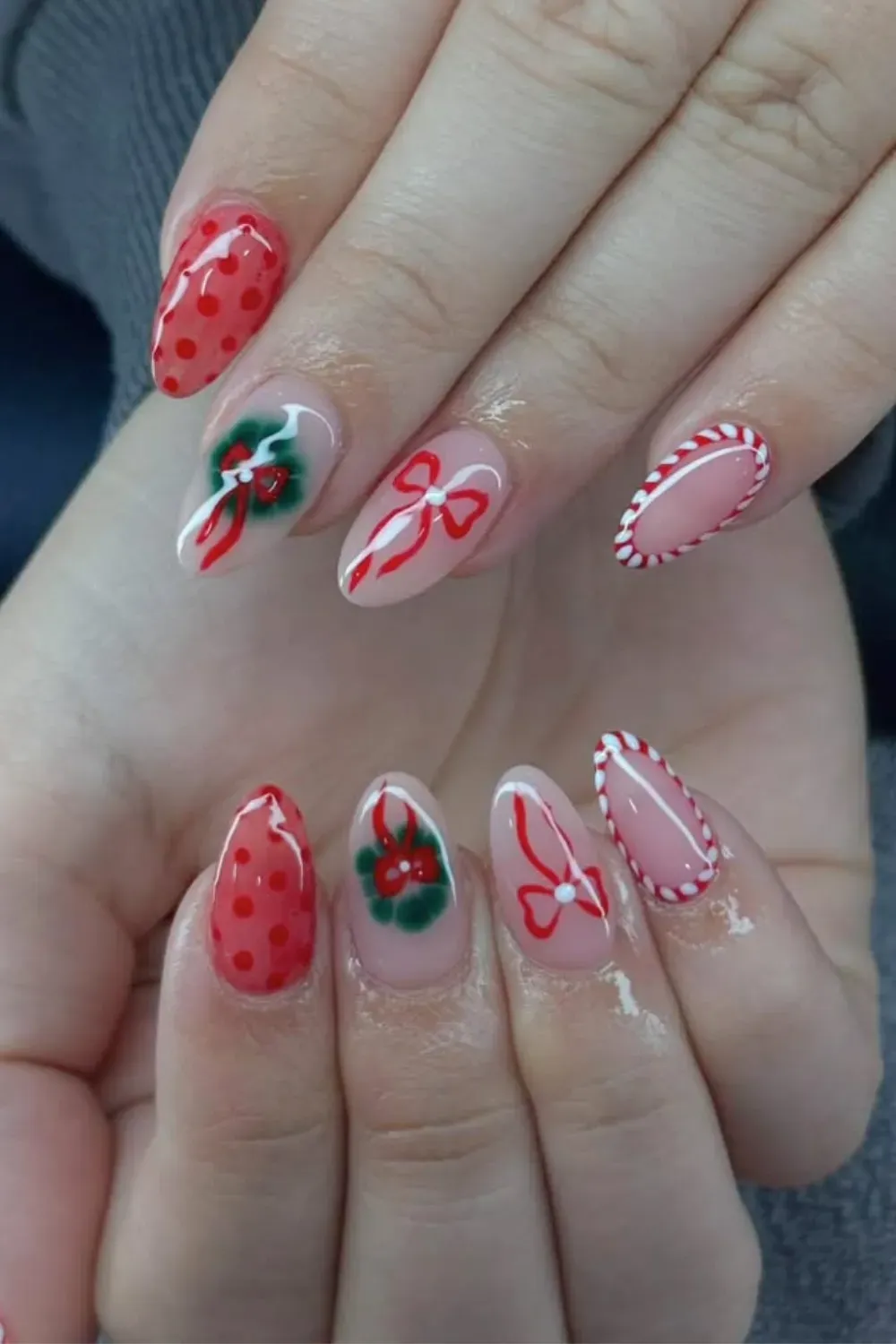 Sheer Nails with Wreaths and Candy Cane Tips - Almond nails with a sheer base, hand-painted wreaths, red bows, and candy cane tips.