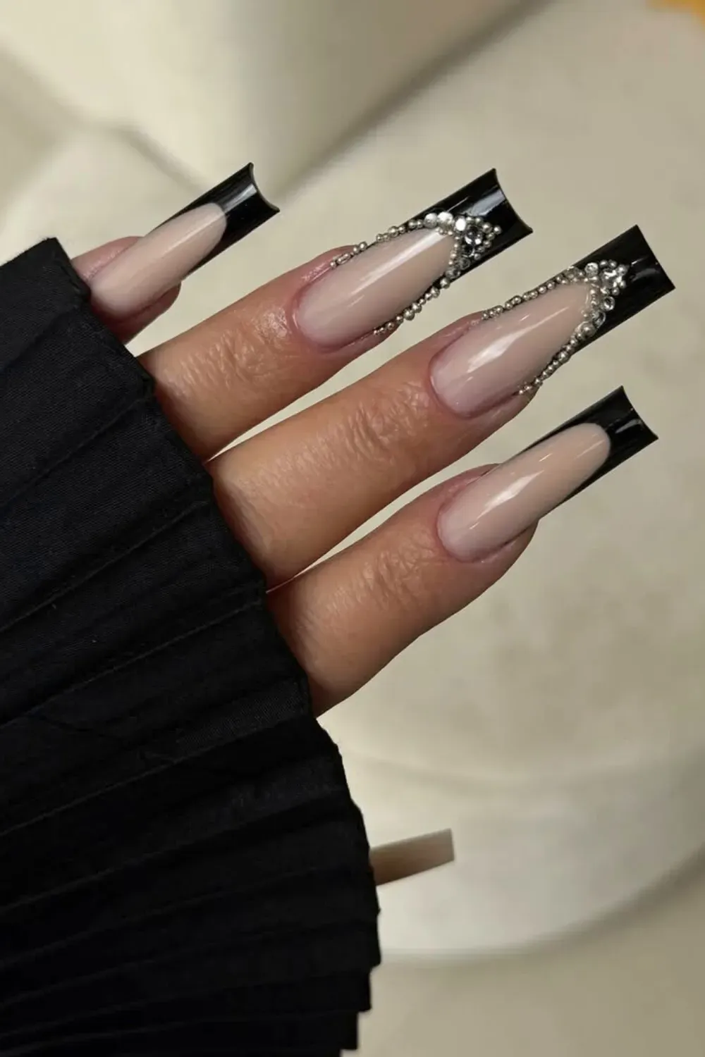 Long square coffin nails with nude base, glossy black tips, and silver rhinestone chain embellishments.