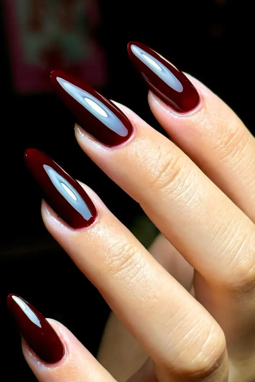 Long, glossy stiletto nails painted a solid, deep dark cherry red.