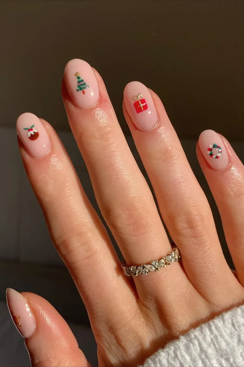 Sheer Pink Nails with Delicate Christmas Miniatures - Oval nails with a sheer pink base and tiny, delicate Christmas icons like a tree and gift