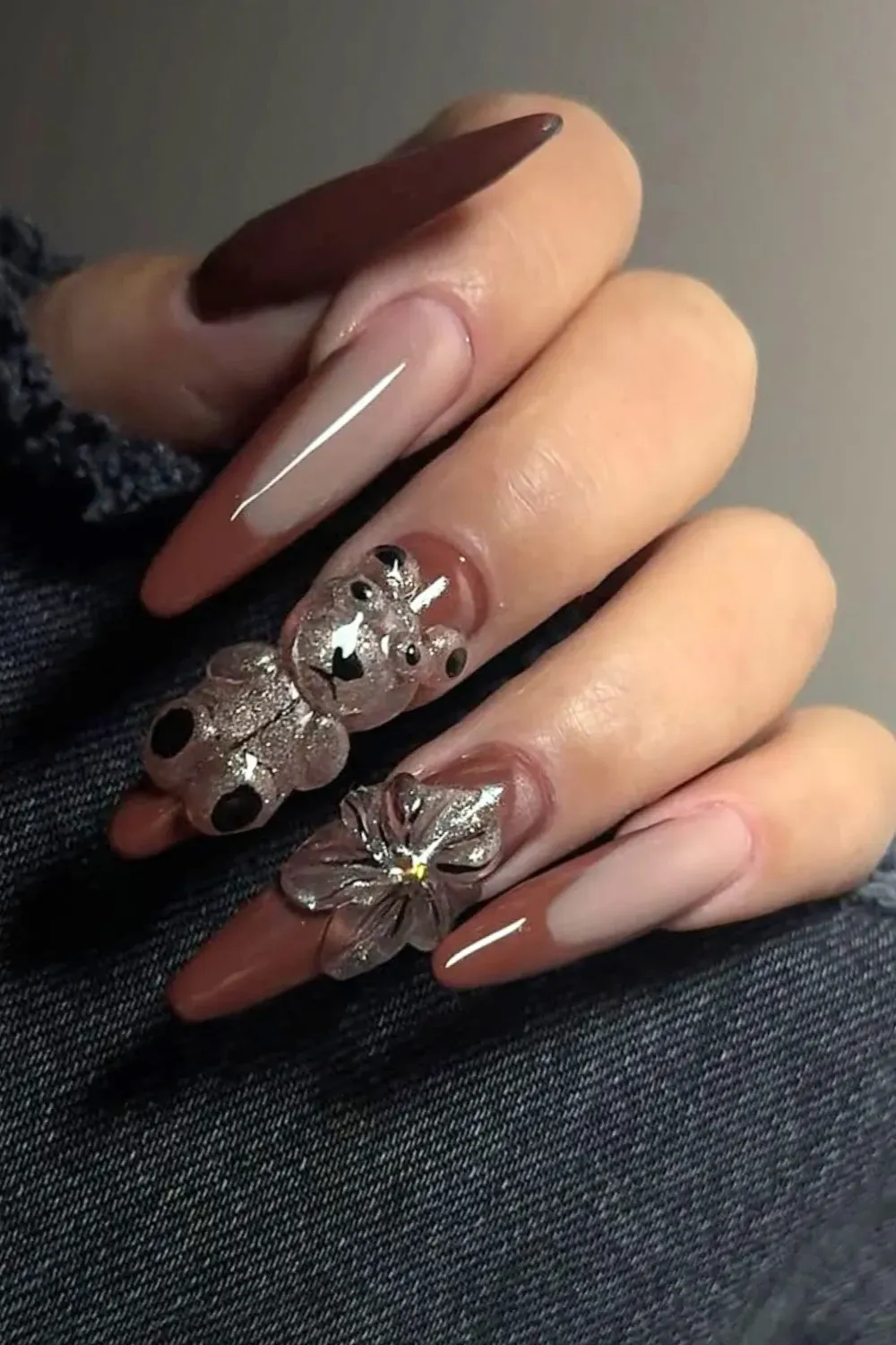 Long stiletto nails in dusty rose with a glittery teddy bear charm and a 3D flower embellishment.