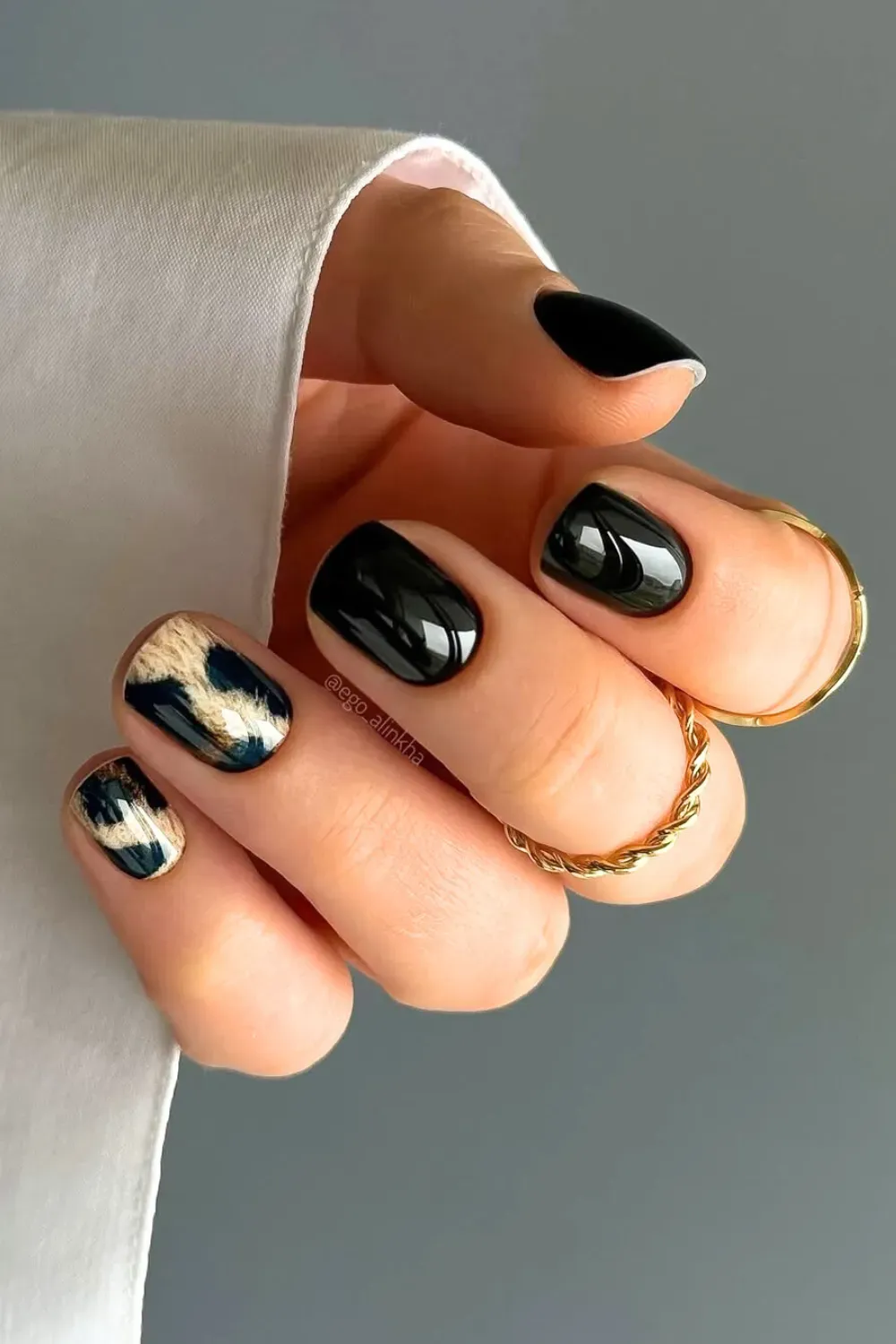 Black Glossy Nails with Animal Print	Hand showing short, rounded black glossy nails with two accent nails featuring a gold and black animal print.