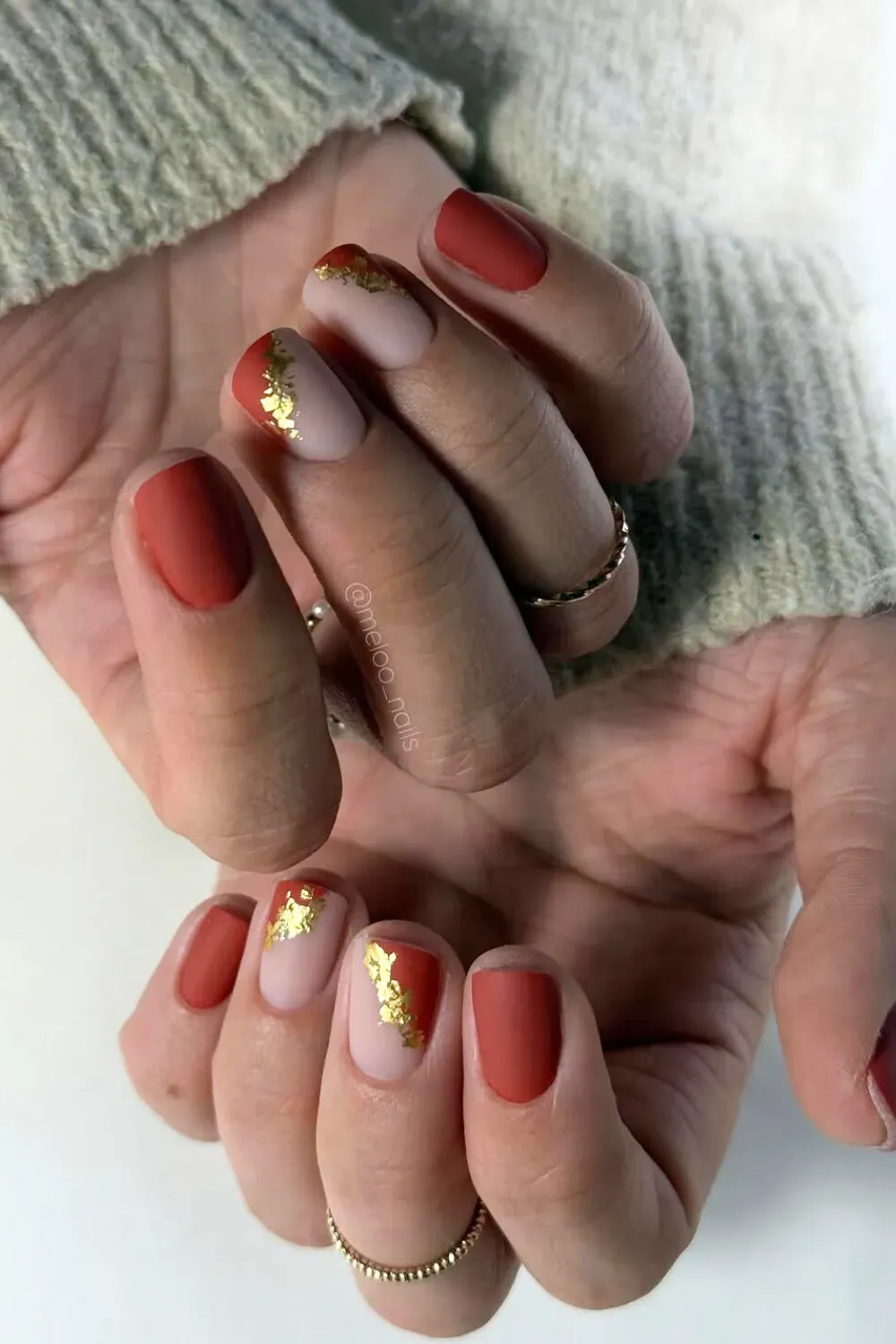 Matte Terracotta and Gold Foil Split Nails Short, rounded-square nails with a matte terracotta block color and a nude color-block, separated by a line of crushed gold leaf/foil.