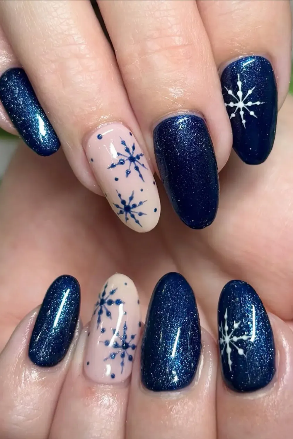 Blue Glitter and Nude Snowflake Oval Nails - Oval nails combining deep blue glitter with nude nails featuring blue snowflakes