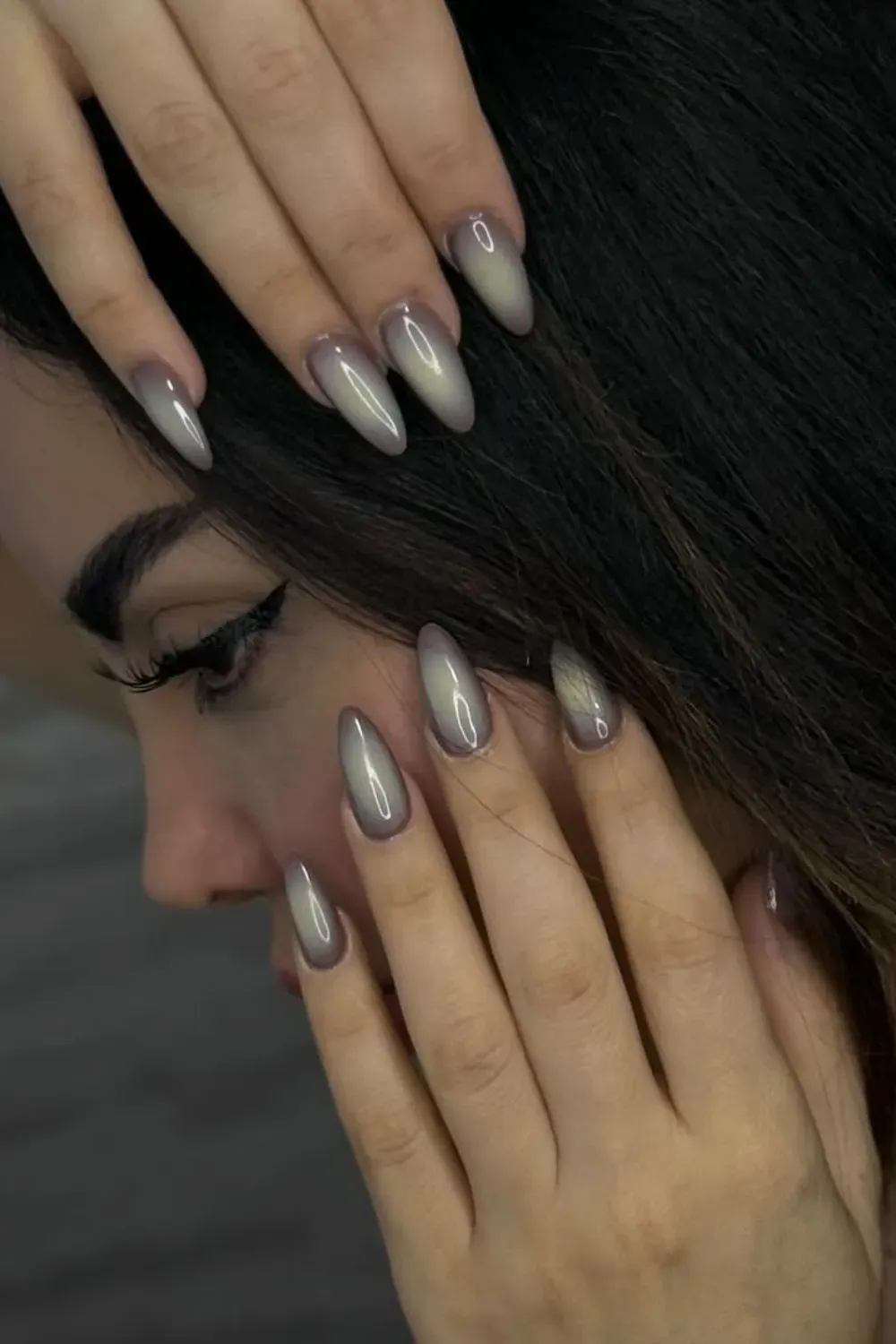 Ethereal Ombre Glam - Long, pointed almond nails with a soft, ethereal ombre blend of milky nude and shimmering grey-mauve cat eye polish.