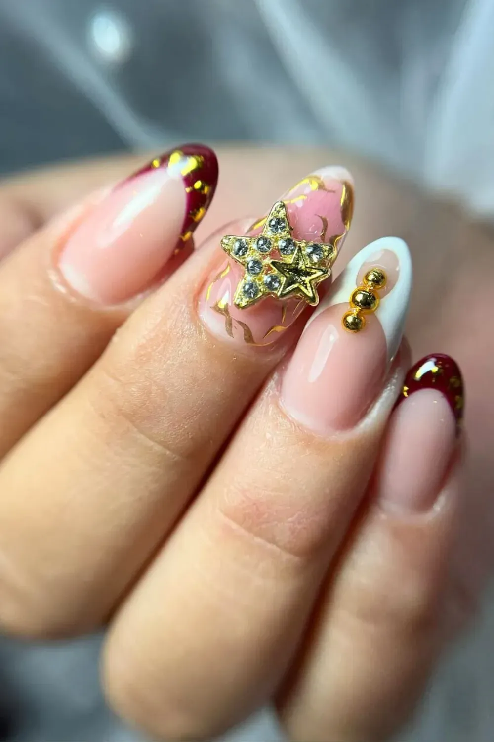Red French Nails with Gold Star Charm - Almond nails with red French tips outlined in gold and a large gold star charm.