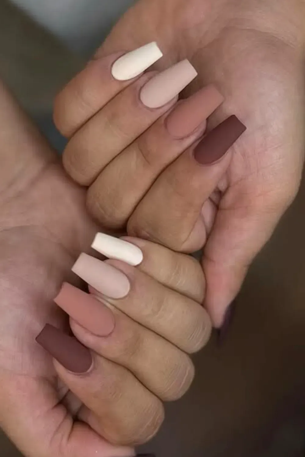Velvet Matte Brown Ombré Coffin Nails Close-up of hands showing long coffin nails with a five-shade matte ombré design in creamy white, beige, taupe, and dark brown.