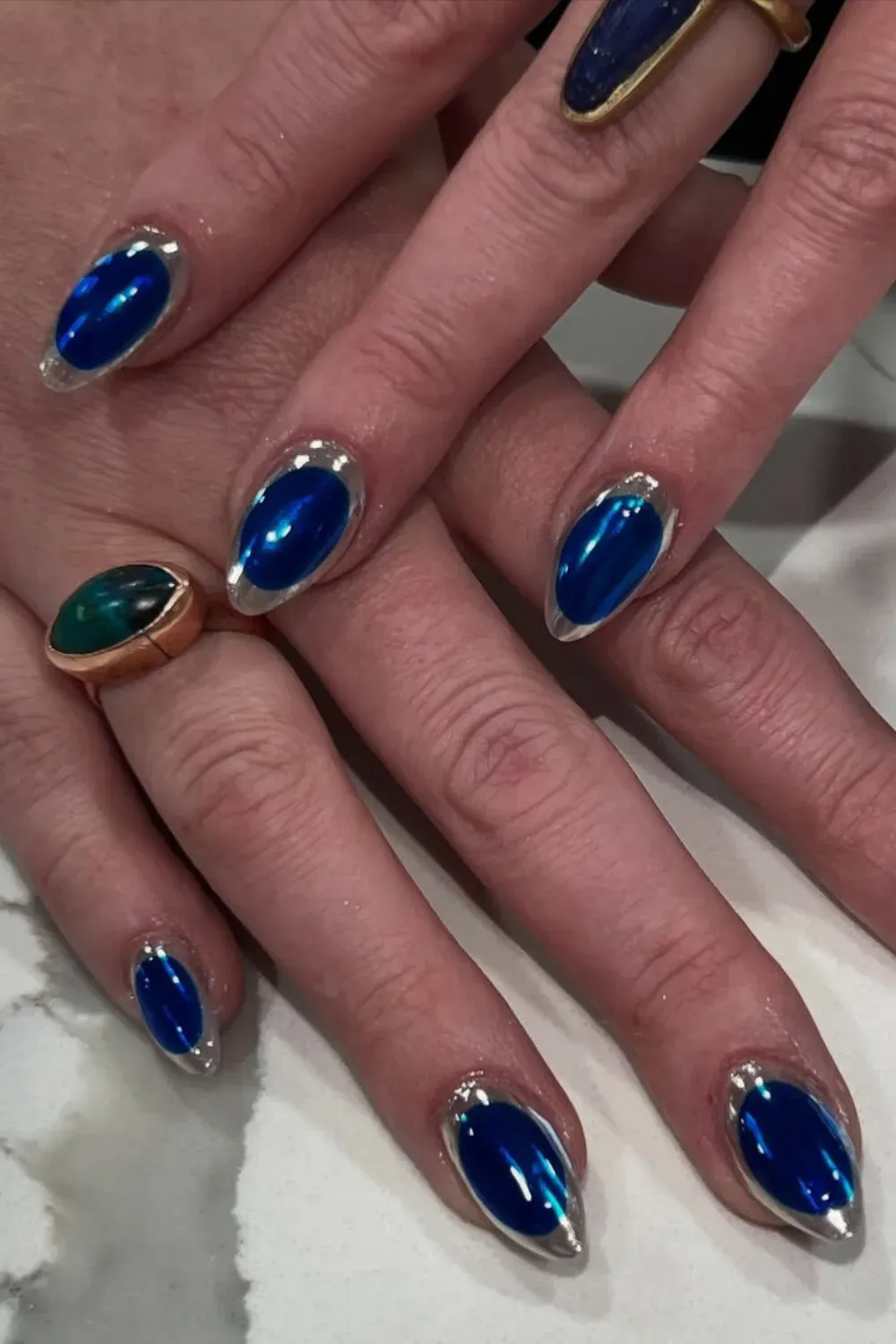 Almond nails with brilliant cobalt blue chrome polish and a metallic silver chrome border.