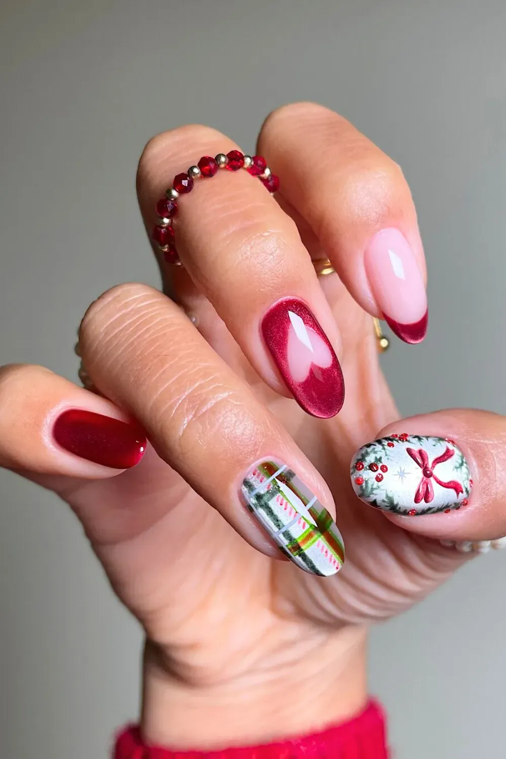 Red Cat-Eye Heart and Plaid Almond Nails - Almond nails featuring a red cat-eye heart, a plaid design, and a painted wreath.