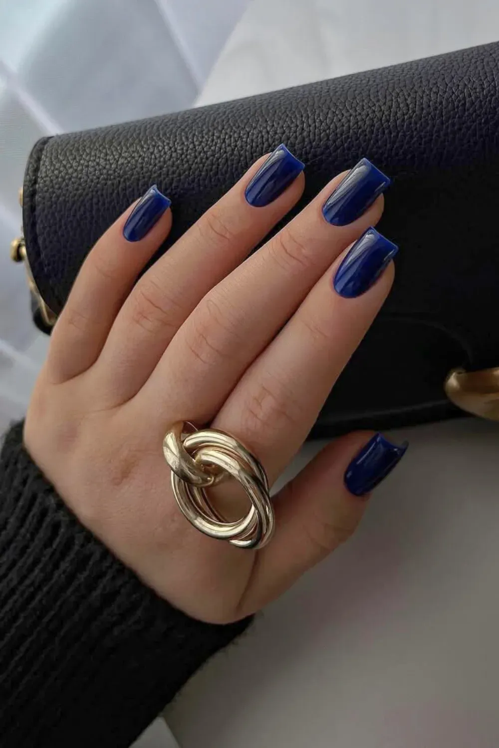 Electric Deep Blue Square Nails	Hand resting on a black purse, featuring squared nails coated in a bright, deep electric blue polish