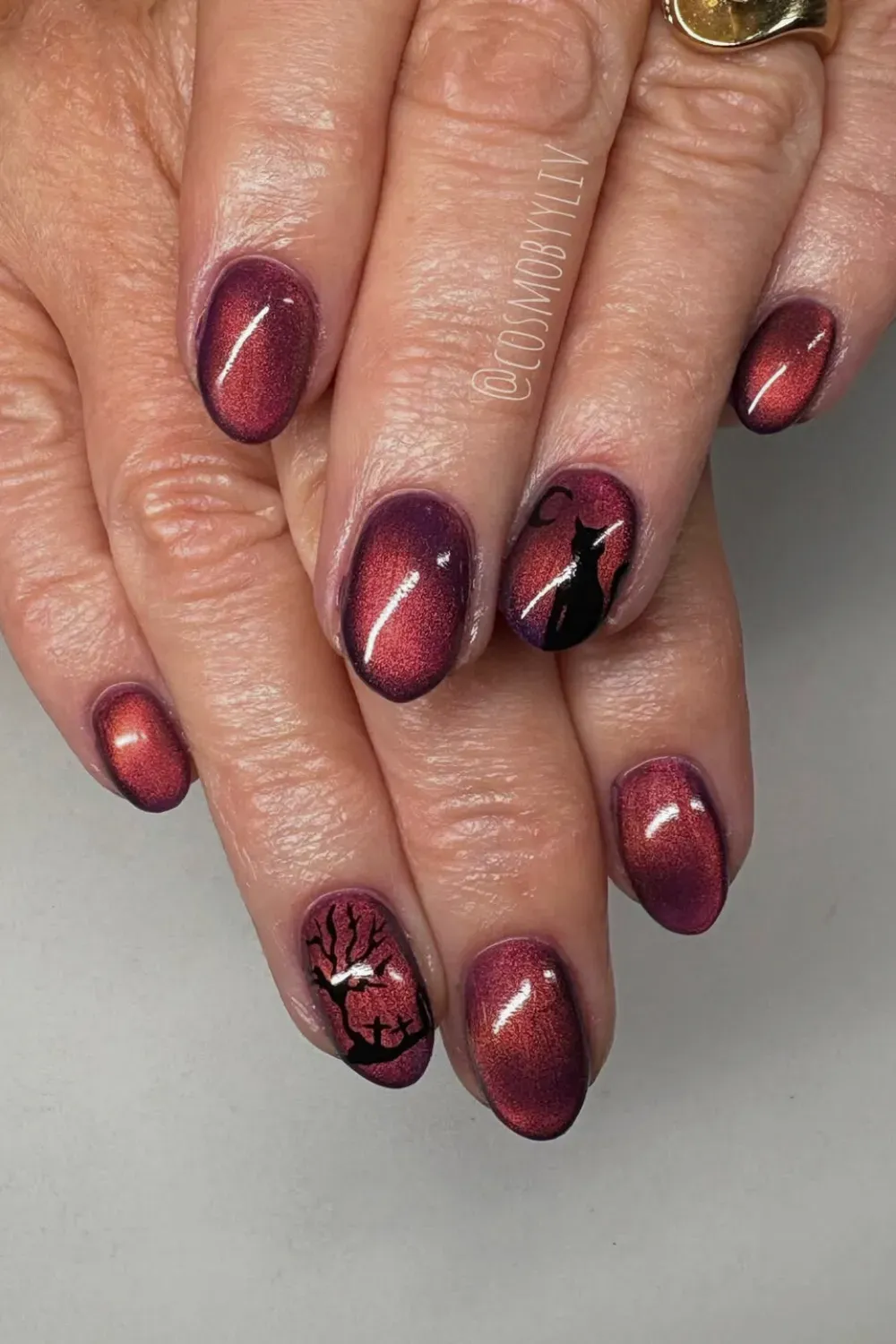 Spooky Silhouettes - Oval nails with a color-shifting red/purple cat eye base, featuring black silhouette stamping art of a witch's cat and a bare tree