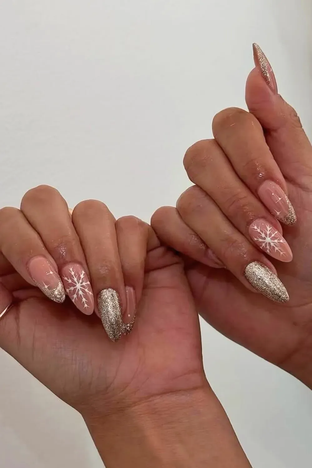 Nude Nails with Silver Glitter Tips and Snowflakes - Almond nails with a sheer nude base, fine silver glitter tips, and delicate snowflakes.