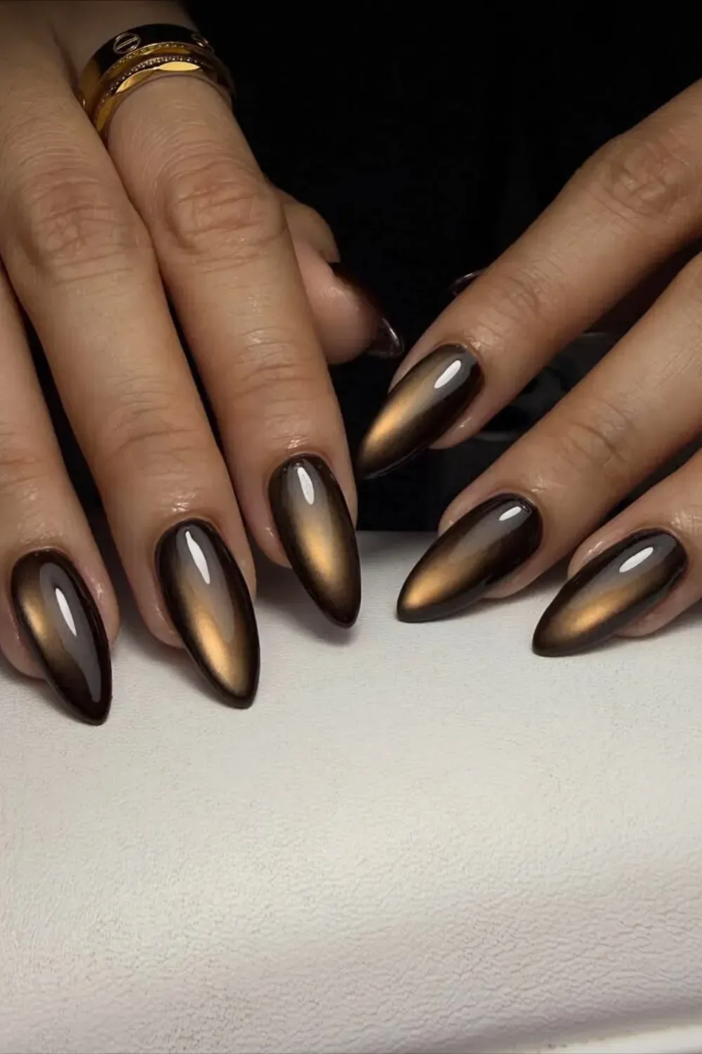 Sleek Golden-Brown Almonds - Long, pointed almond nails coated in a high-gloss, deep chocolate brown cat eye polish with a prominent golden light reflection.