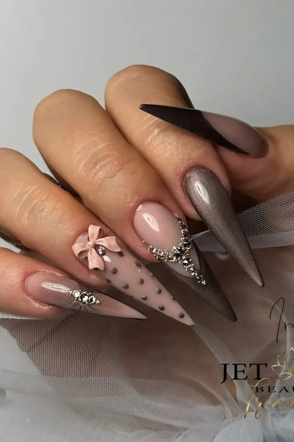 The Ultimate Autumn Mix - Dramatic long stiletto nails featuring a dark brown cat eye, nude accent with a 3D nude bow, polka dots, and a rhinestone cascade.