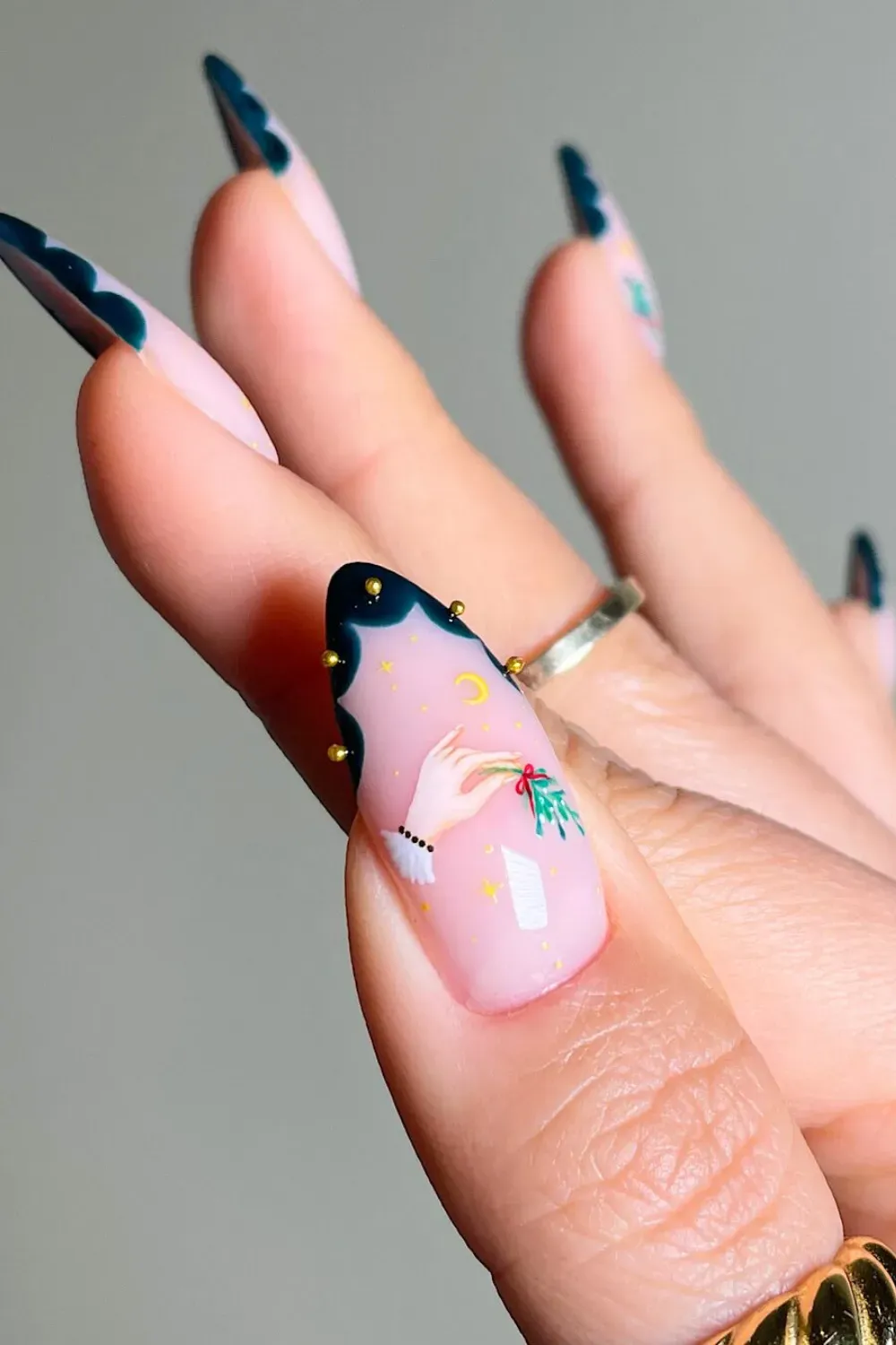 Green Tip Stiletto Nails with Mistletoe Hand Art - Stiletto nails with dark green tips and an accent nail with a painting of a hand holding mistletoe