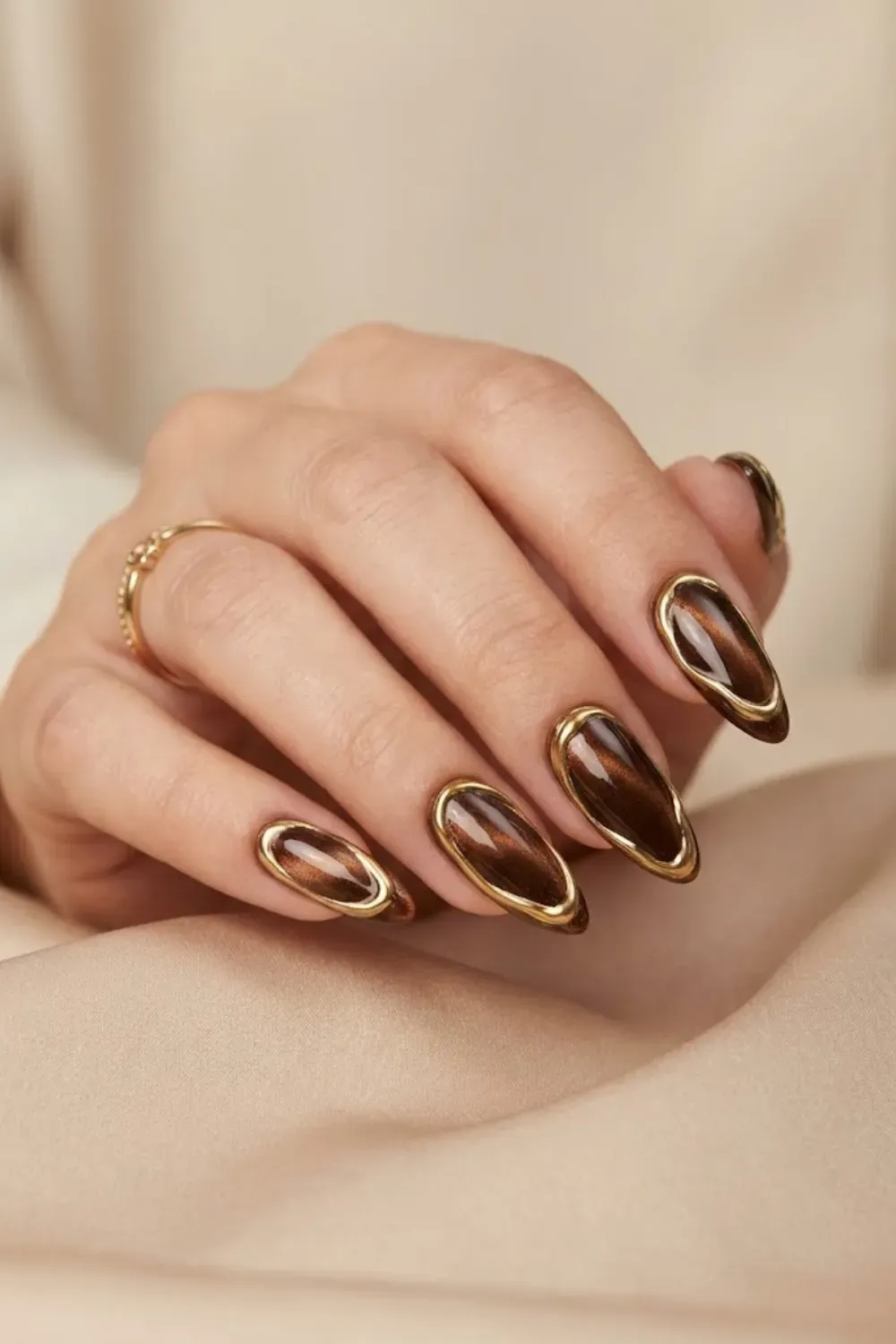 Abstract gold and brown chrome cat eye nails with molten gold outlines creating a luxury magnetic nail art design