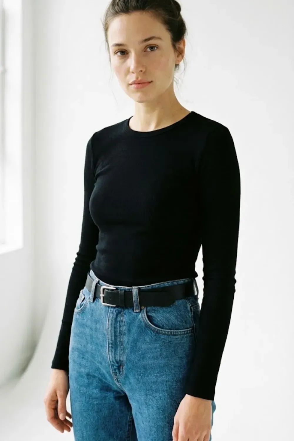 Minimal Black Tee & Blue Jeans - Minimalist outfit featuring a fitted black long sleeve top tucked into blue jeans with a black belt.