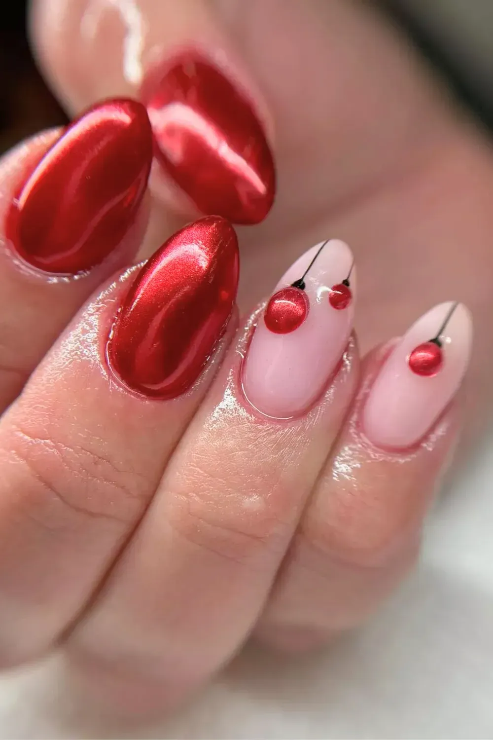 Red Chrome and Hanging Ornament Nail Art - Red chrome nails paired with a pink accent nail featuring hanging red chrome ornaments.