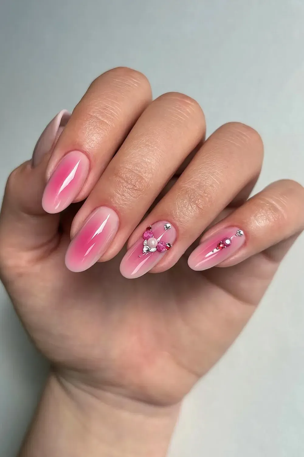 Magical Pink Aura - Oval nails with a pink aura airbrush effect and small gemstone embellishments.