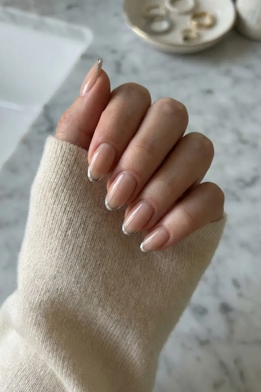 Silver Chrome French Tips – Oval nude nails featuring trendy metallic silver chrome french tips.