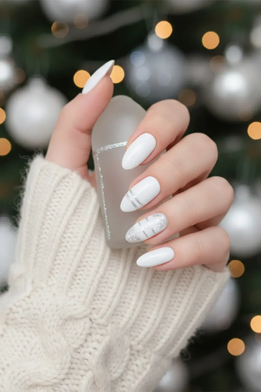 White Nails with Silver Ornament Stripes - Hand holding an ornament featuring white nails with silver glitter geometric stripes and bauble designs.