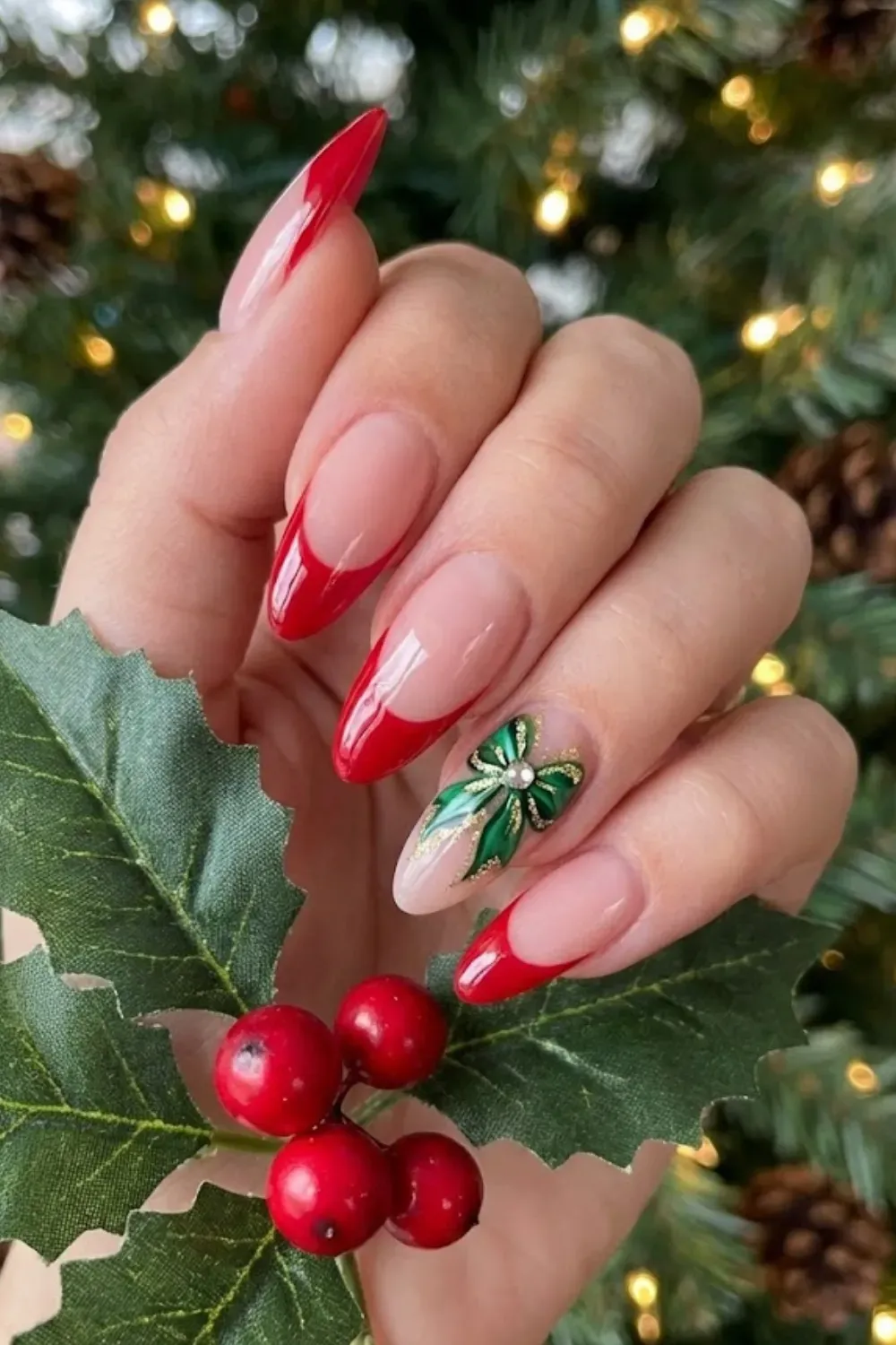 Festive Bow Holly Nails — long almond nails with red tips and a large 3D green bow and holly charm.
