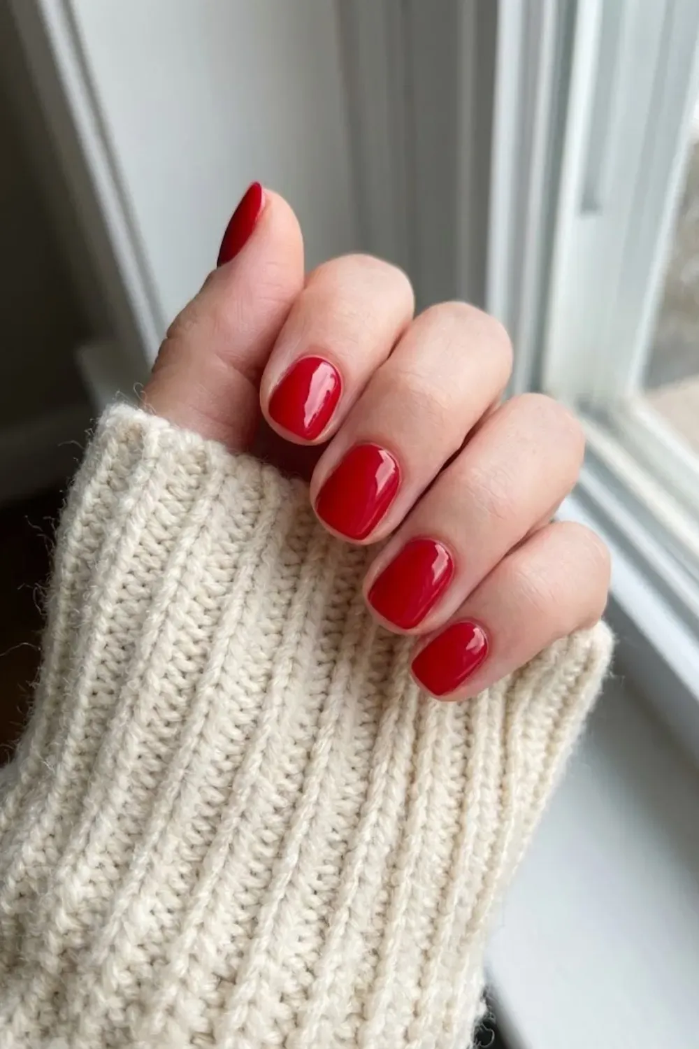 Classic Red Short Round - Timeless short round nails painted in a vibrant candy apple red gloss, styled with a cozy cream sweater.