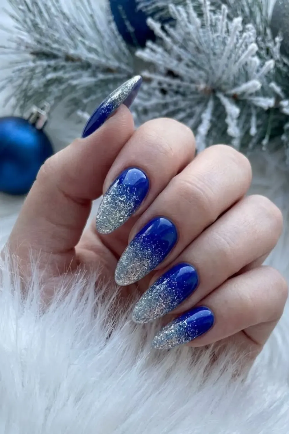 Royal Blue to Silver Glitter Ombré - Hand holding an ornament featuring deep blue nails fading into sparkling silver glitter at the tips.