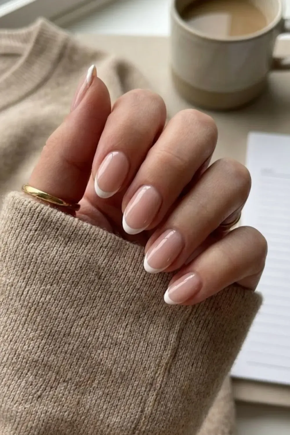 Classic White Tip French Manicure – Oval-shaped nails with a traditional white french tip and sheer pink base, styled with a gold ring.