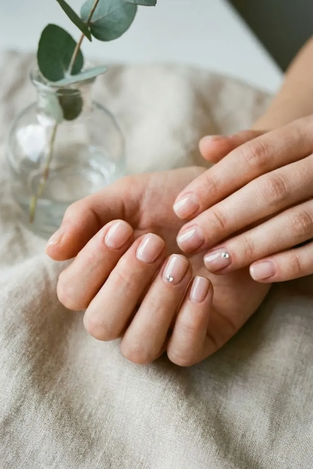 clear-glossy-nails-gem-accent - Clear glossy nails with a single tiny gem accent, minimalist clean girl style.