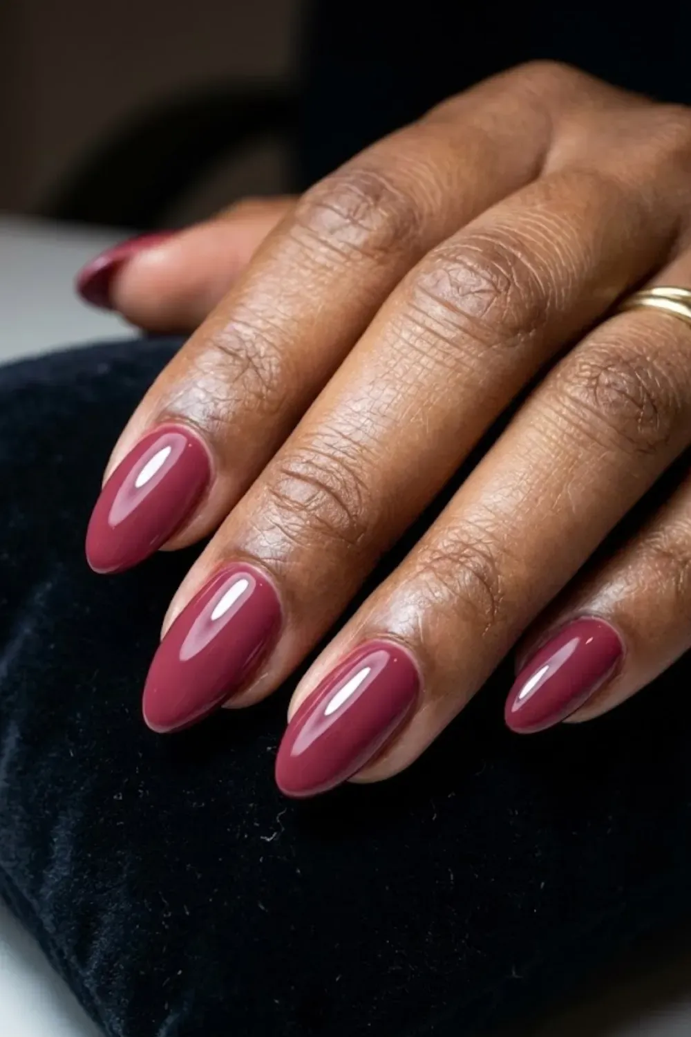 Dusty Rose Mauve Almond Nails – Glossy almond-shaped nails in a deep dusty rose mauve shade, styled on a black velvet cushion.