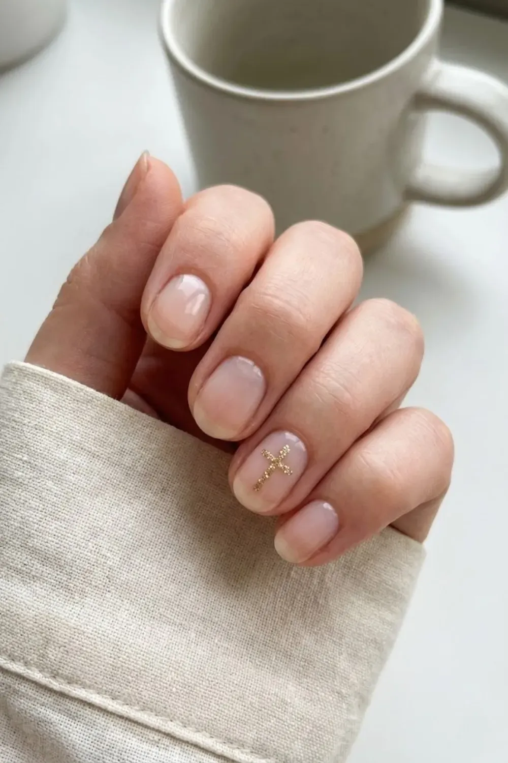 Minimalist Gold Glitter Cross - Short natural nails accented with a tiny, delicate gold glitter cross design for a subtle artistic touch.