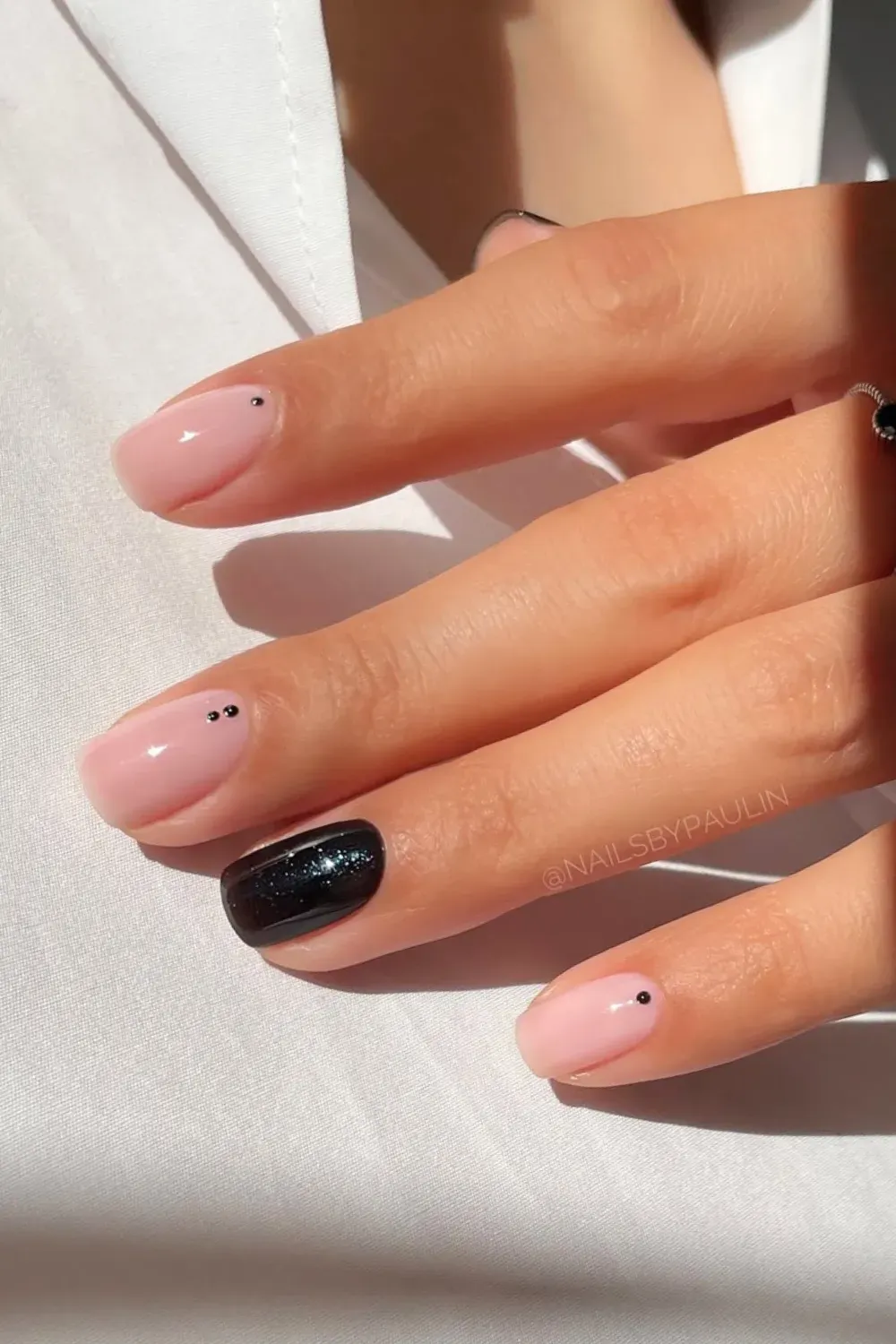 Subtle Dots and Glitter	Nude nails with black dots and one black glitter nail